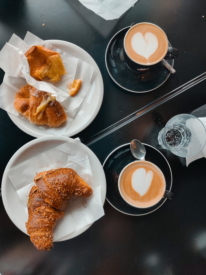 Top view of croissants and coffee with heart latte art at a cafe in Latina, Lazio, Italy.
